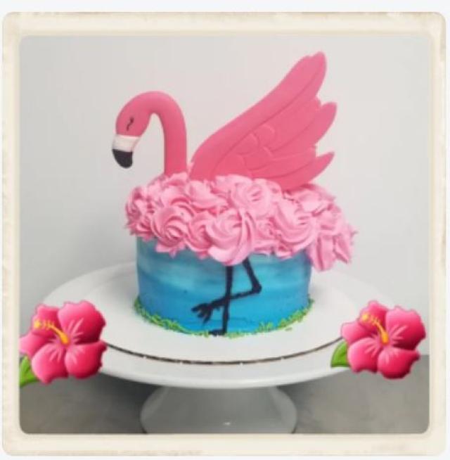 A cake made to look like a flamingo is walking alongside the water.